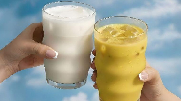 2 vasos con el cielo de fondo uno con leche de coco y otro con una golden milk